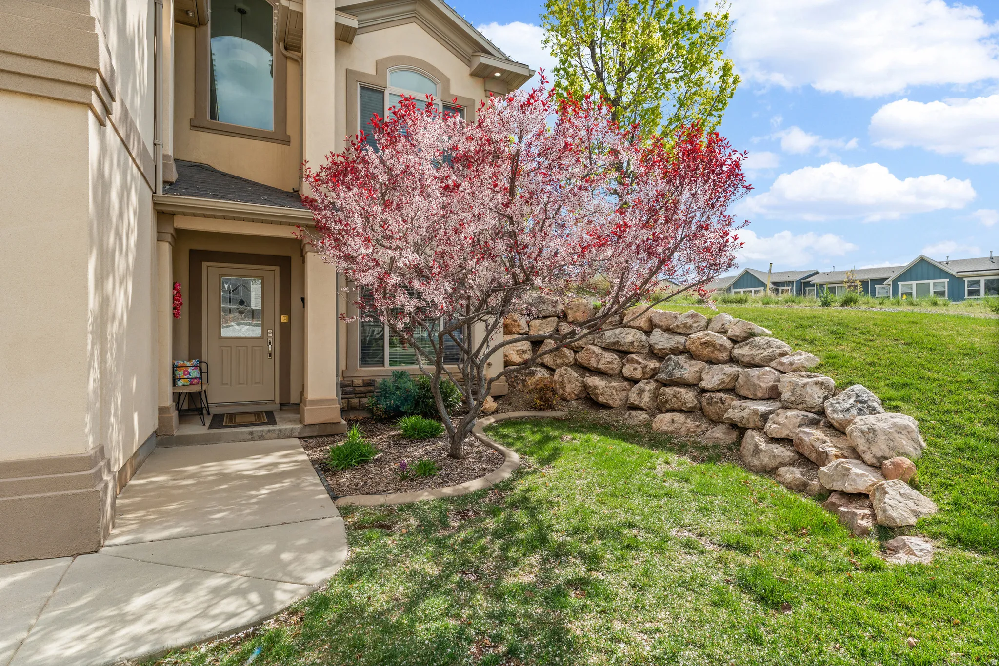 View of exterior entry featuring a lawn, stucco siding, and a shingled roof