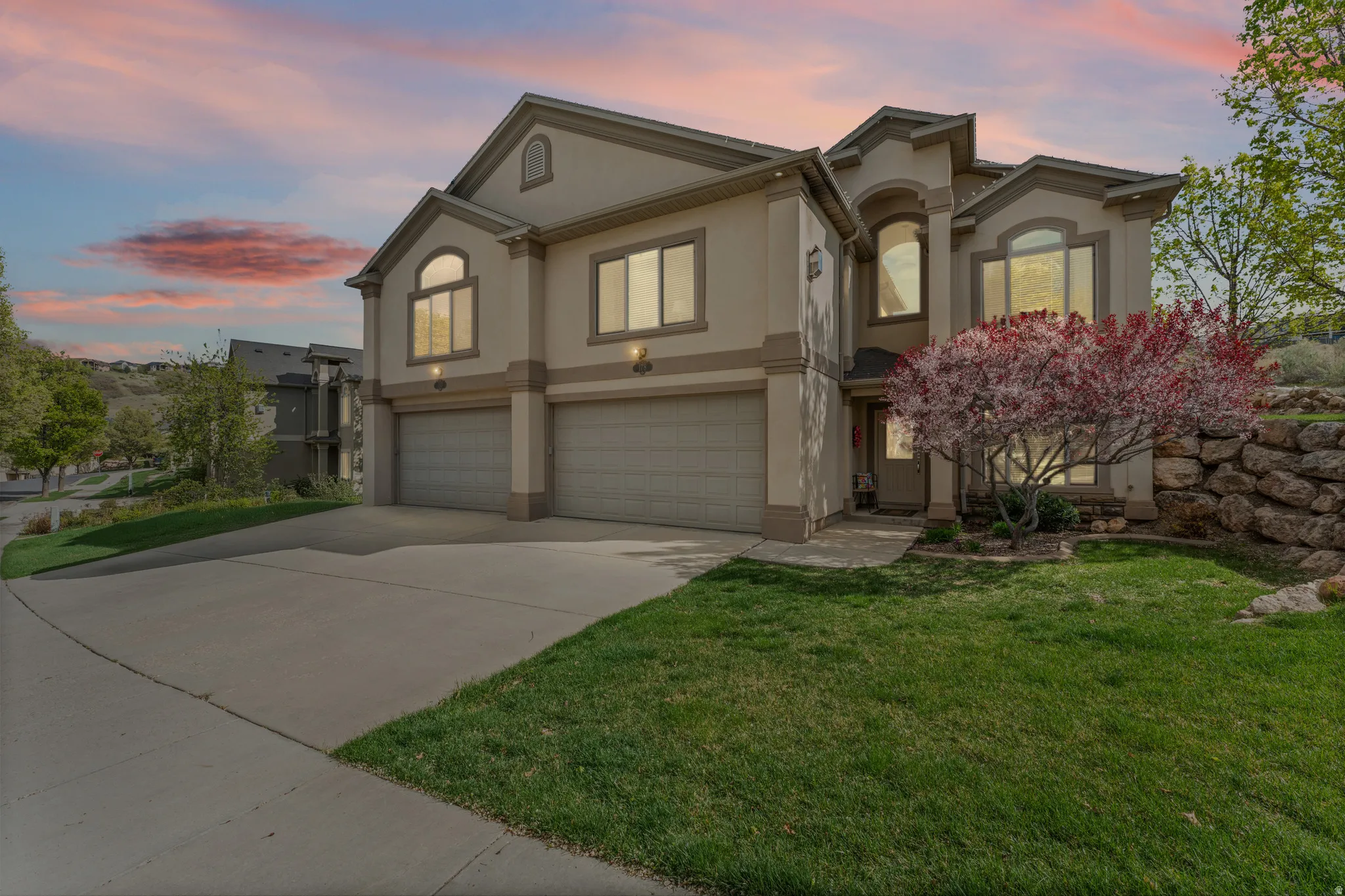 View of front of property featuring stucco siding, a garage, concrete driveway, and a front lawn