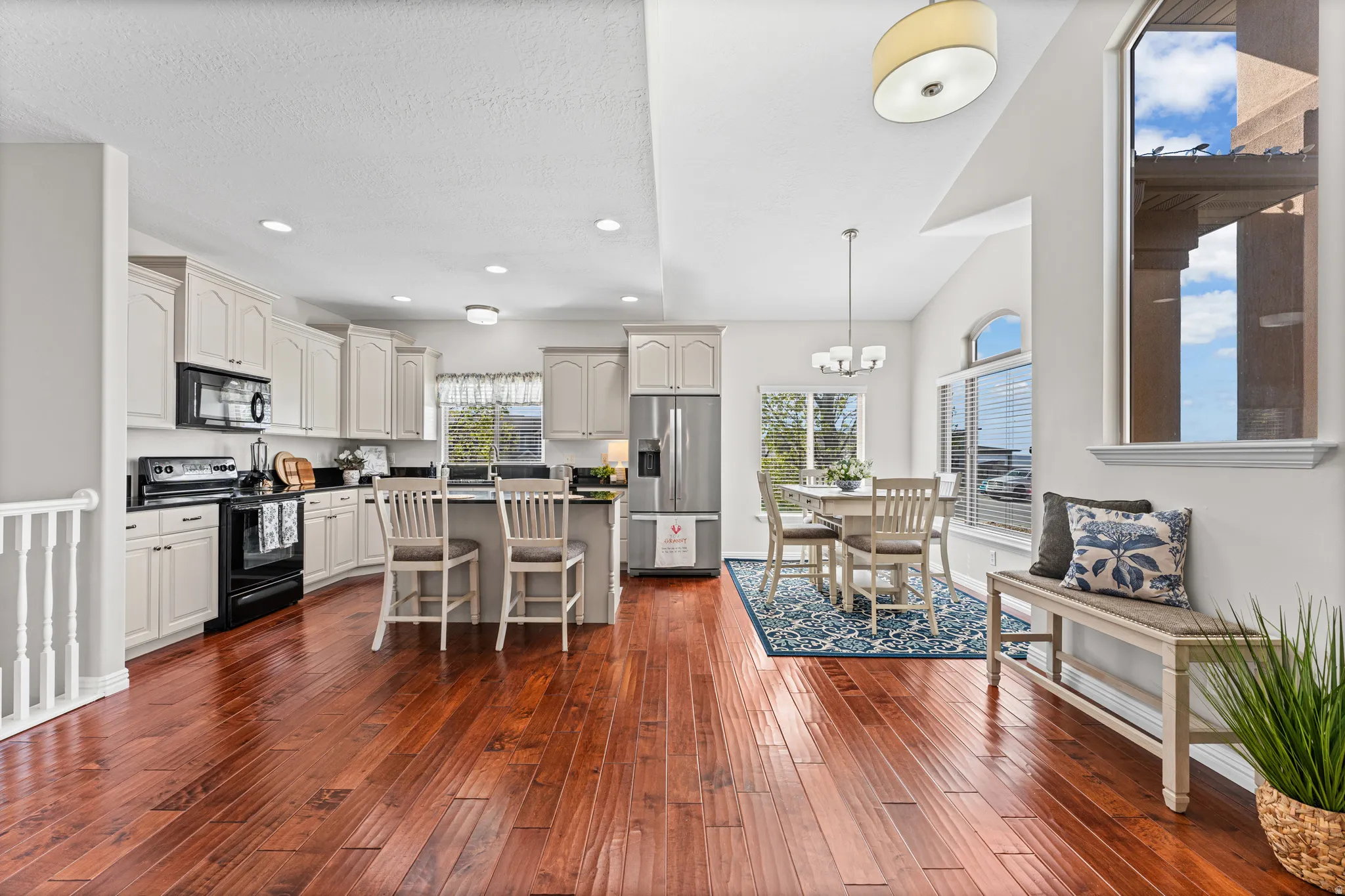 Kitchen featuring a breakfast bar, black appliances, dark wood-style flooring, a kitchen island, and hanging lights