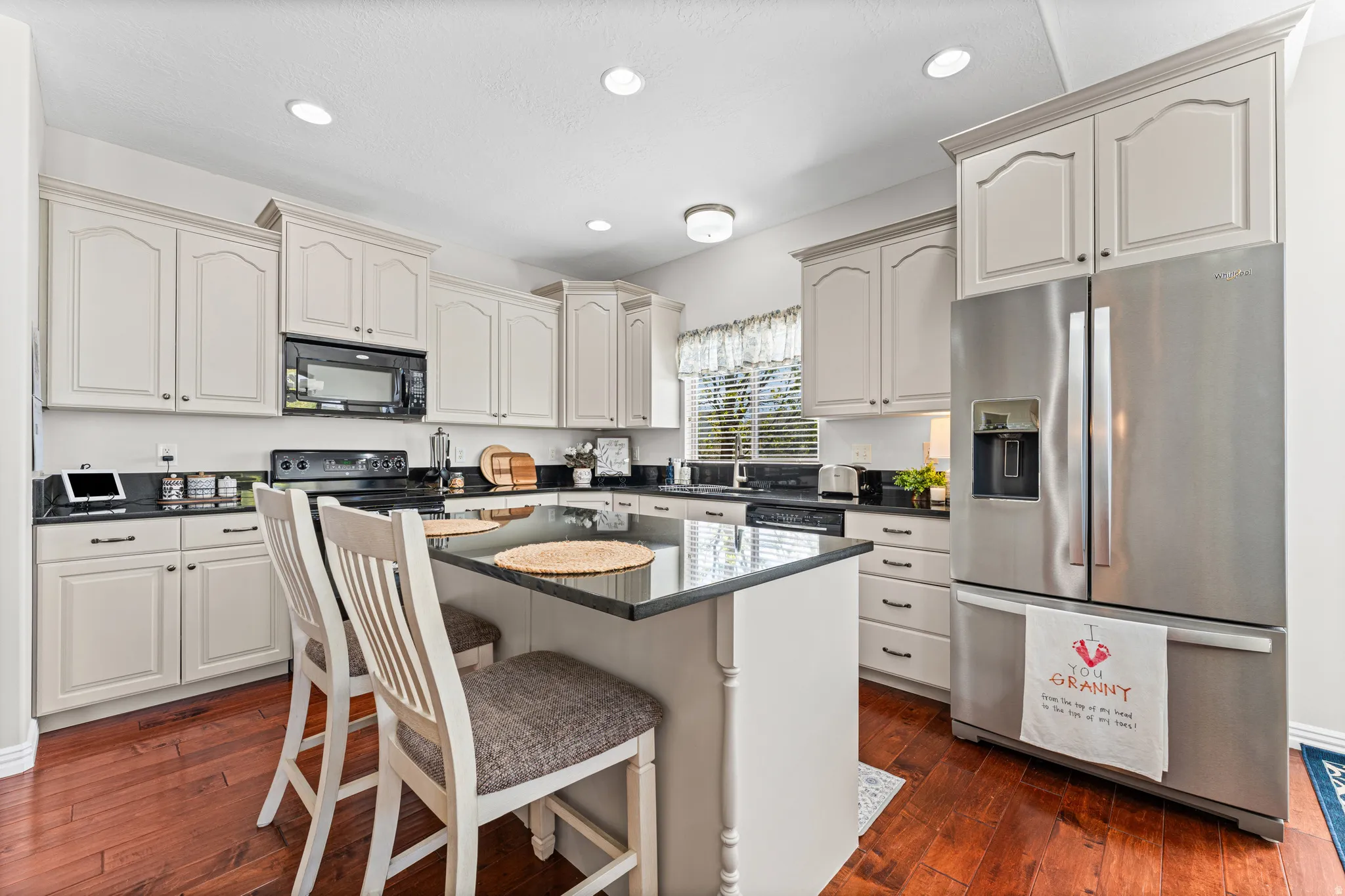 Kitchen featuring black appliances, a kitchen breakfast bar, dark wood-style flooring, a kitchen island, and recessed lighting