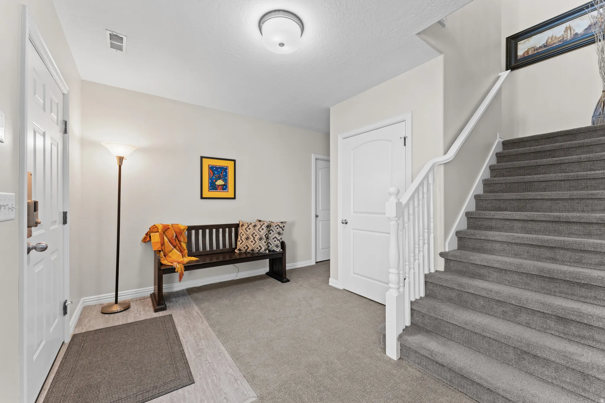 Foyer with stairs and light colored carpet