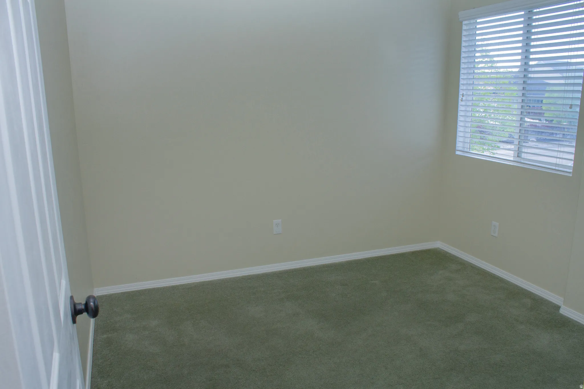 Carpeted spare room featuring baseboards