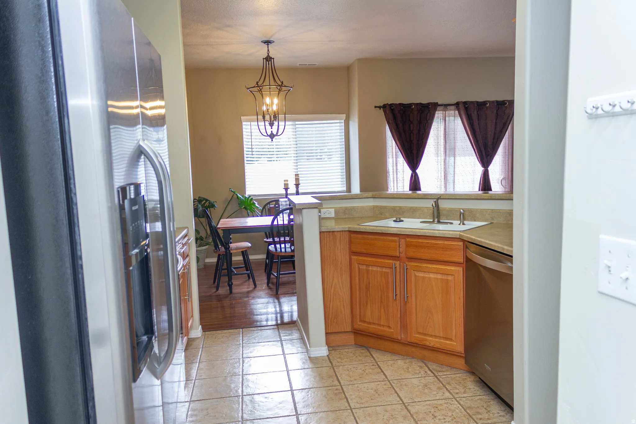 Kitchen featuring stainless steel appliances, light countertops, wood finish cabinets, a chandelier, and a peninsula