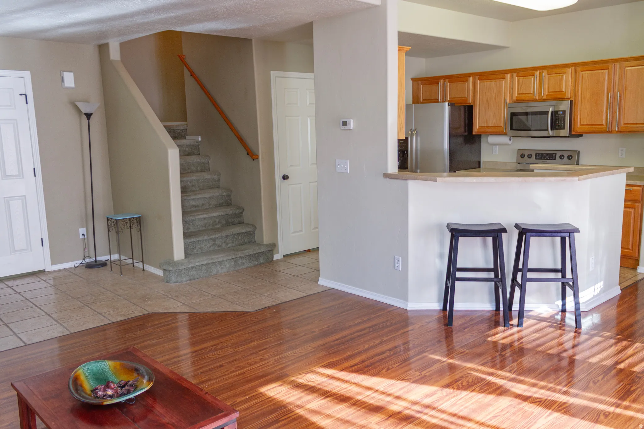 Kitchen featuring light wood-style floors, stainless steel appliances, a kitchen bar, light countertops, and a peninsula