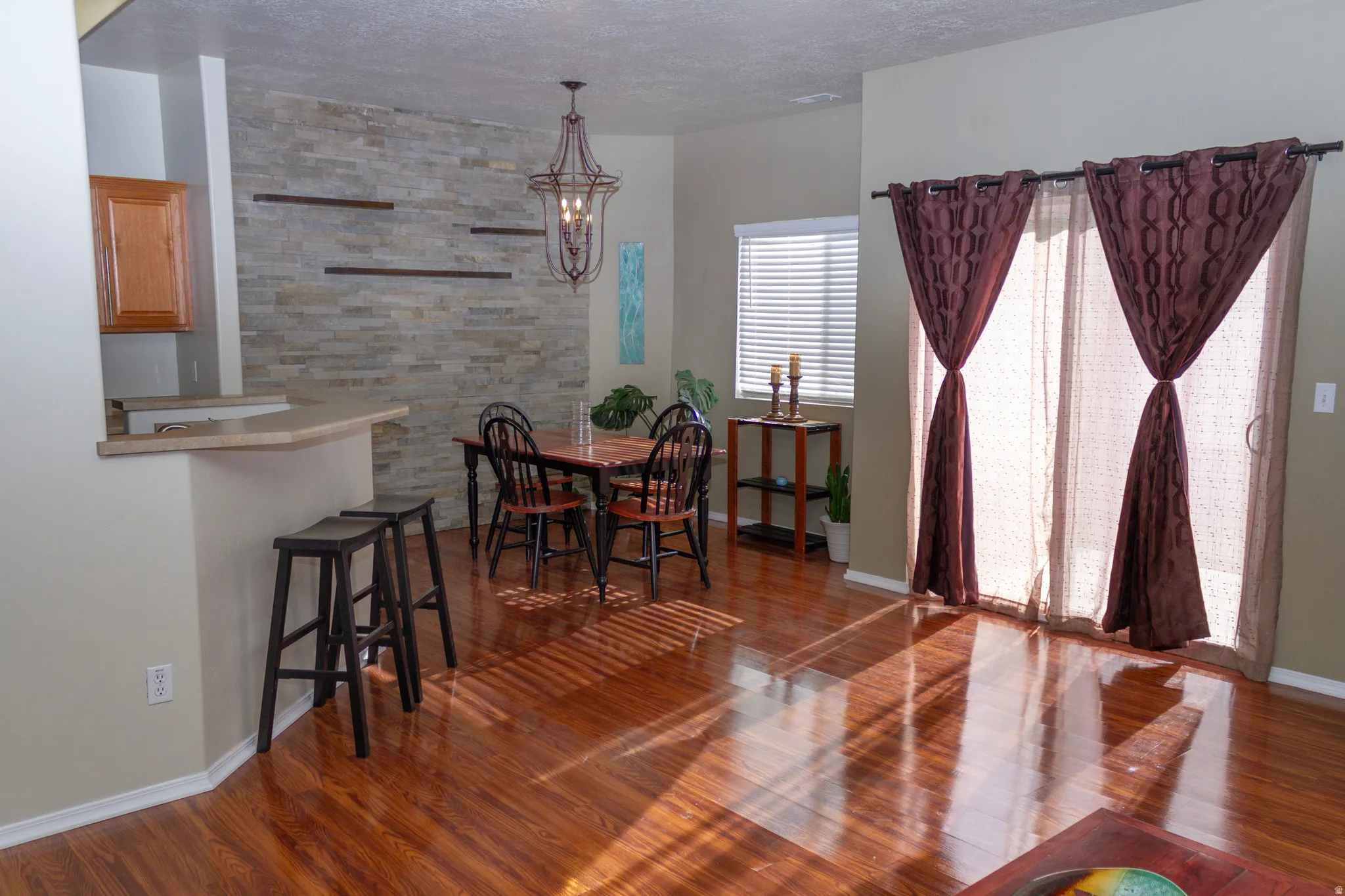 Dining area featuring dark wood-type flooring, suspended lighting, and a textured ceiling