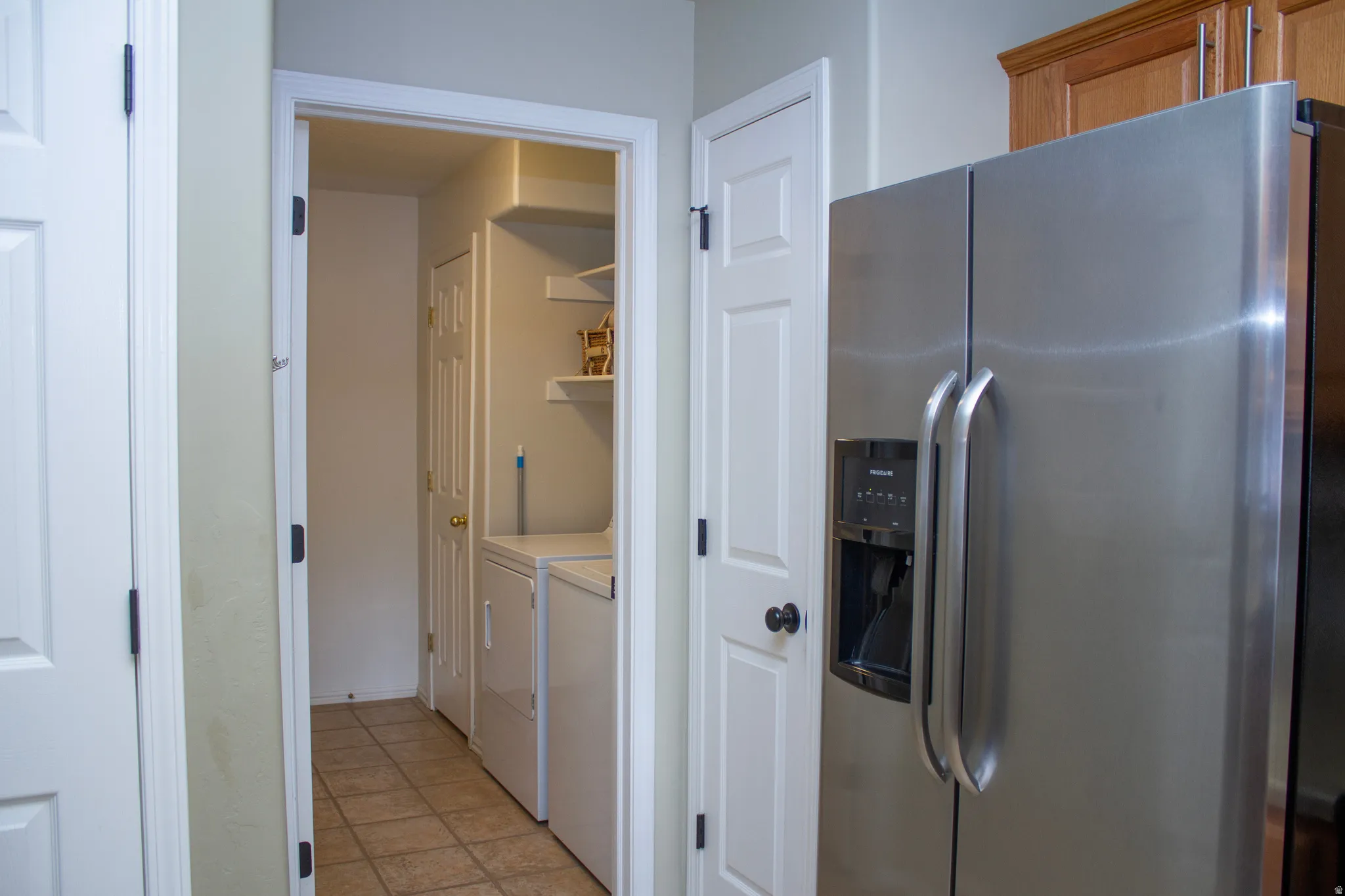 Laundry area with washer and dryer and light tile patterned floors