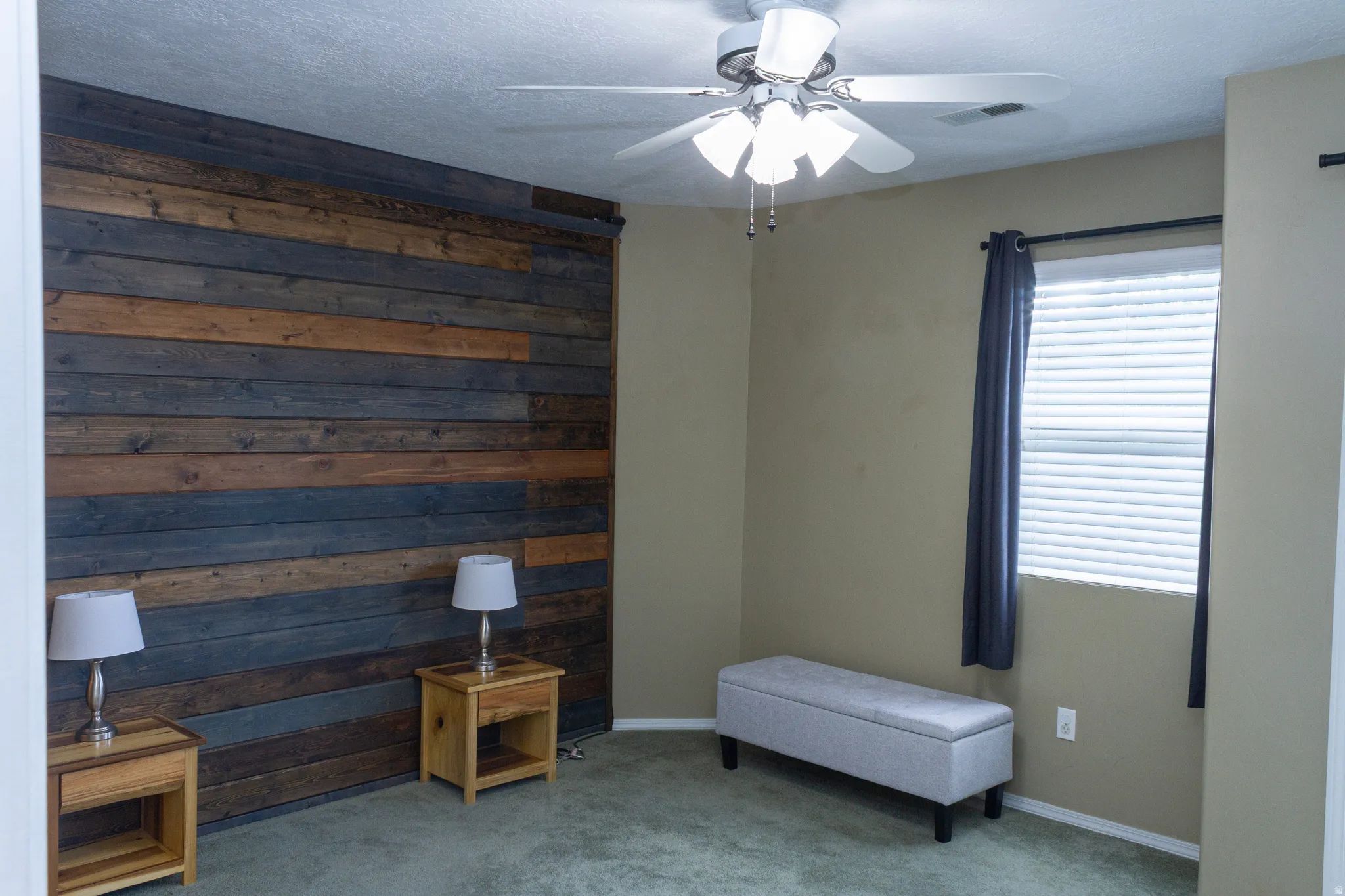 Sitting room with a ceiling fan, carpet, and wood walls