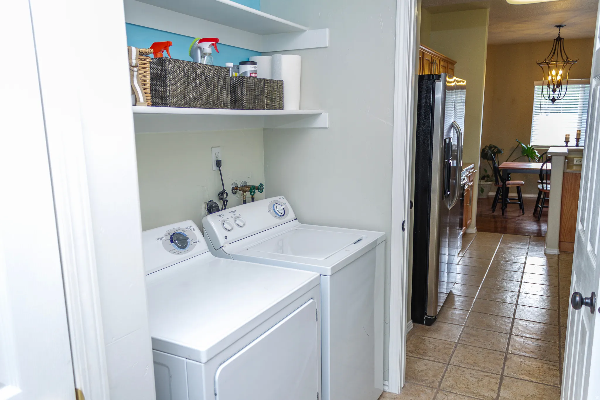 Laundry area with separate washer and dryer, suspended lighting, and light tile patterned floors