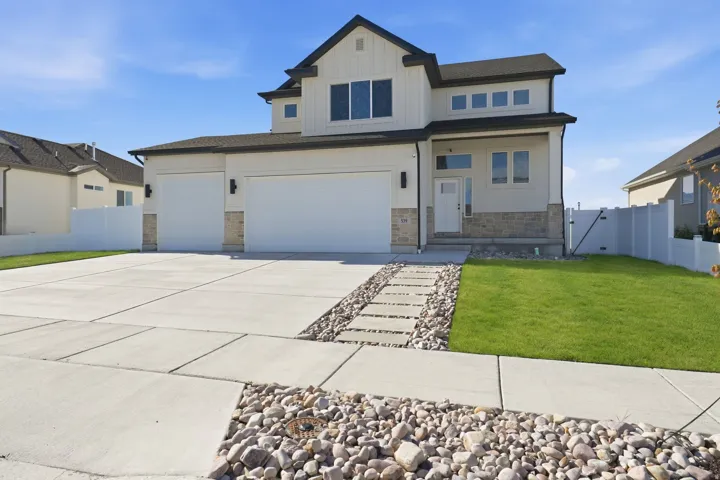 View of front of property featuring a gate, board and batten siding, stone siding, driveway, and an attached garage