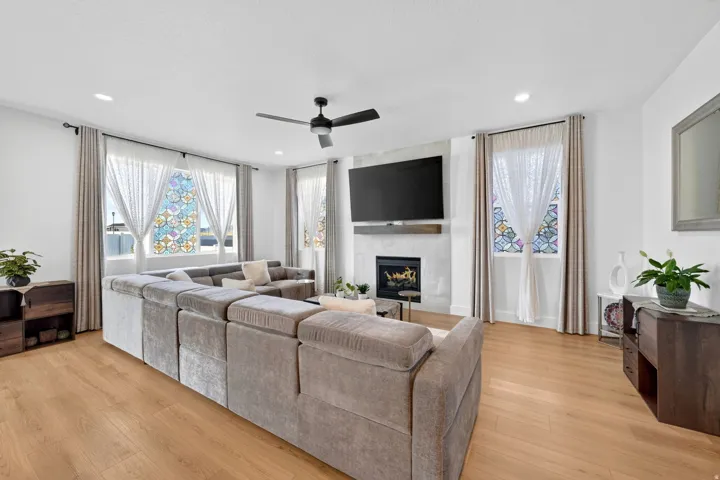 Living room with a ceiling fan, light wood finished floors, and a fireplace