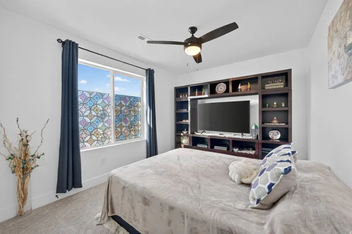 Bedroom with ceiling fan and light carpet