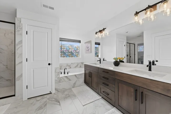 Full bath with a marble finish shower, double vanity, a bath, light marble finish floors, and a closet