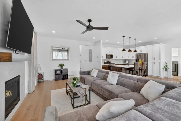 Living area featuring light wood-style floors, a tiled fireplace, a textured ceiling, a ceiling fan, and recessed lighting