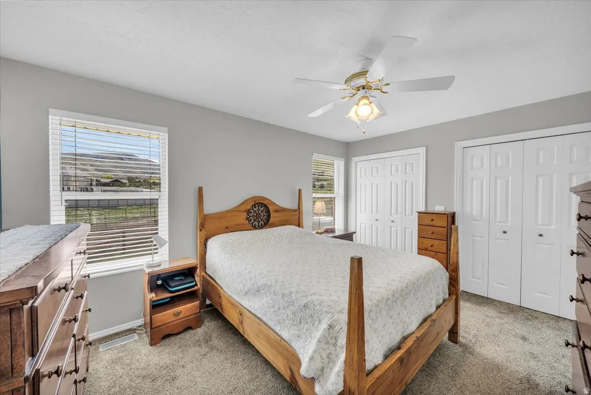 Owner's suite with with multiple closets, ceiling fan, and private bathroom.