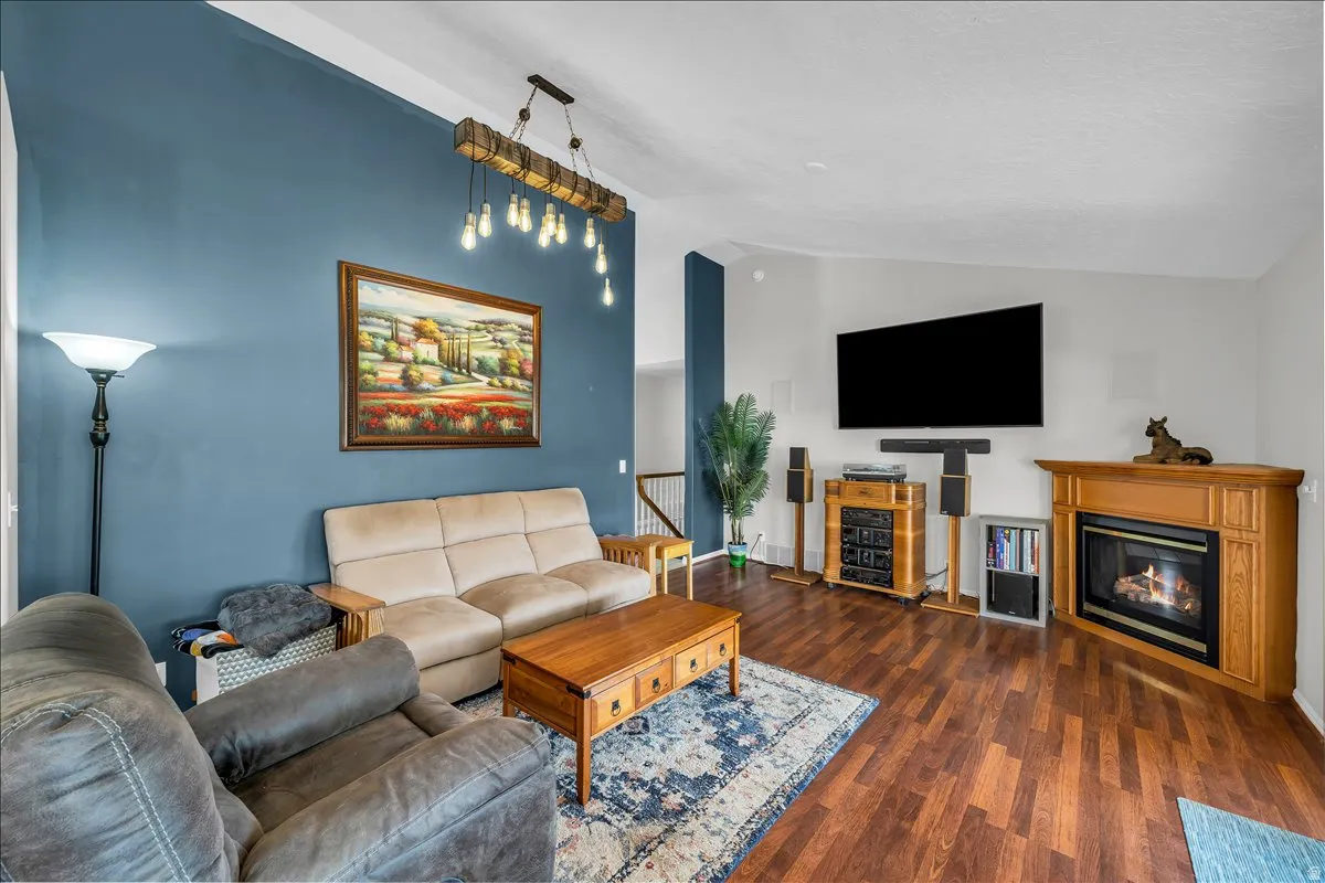Living room featuring lofted ceiling, dark wood-type flooring, and a glass covered fireplace