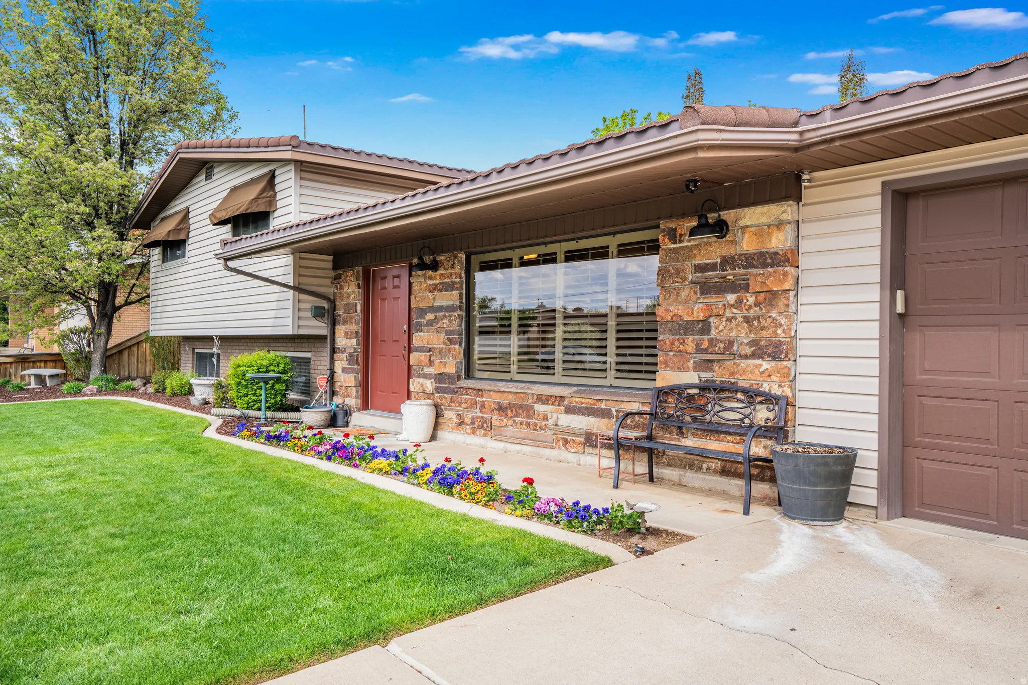 View of exterior entry with a lawn, a metal roof, and stone work