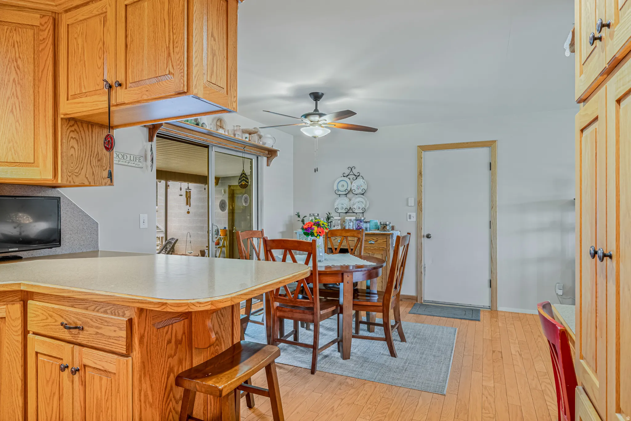 Kitchen with light countertops, light wood finished floors, a ceiling fan, a kitchen bar, and wood finish cabinets