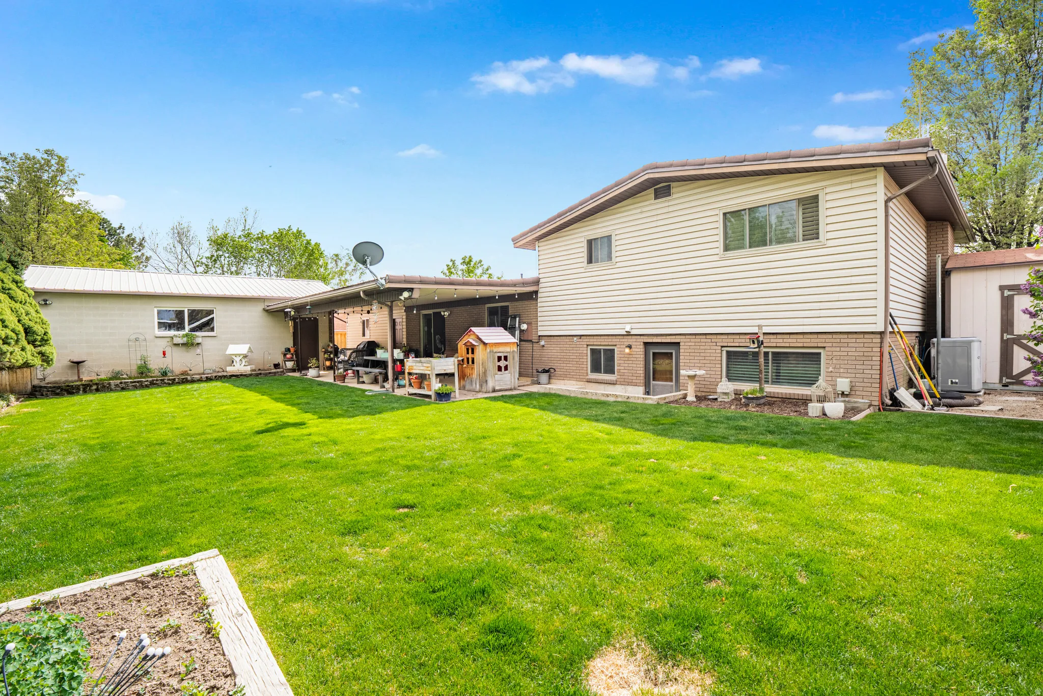 Rear view of house featuring a covered patio, a mature yard, and detached garage