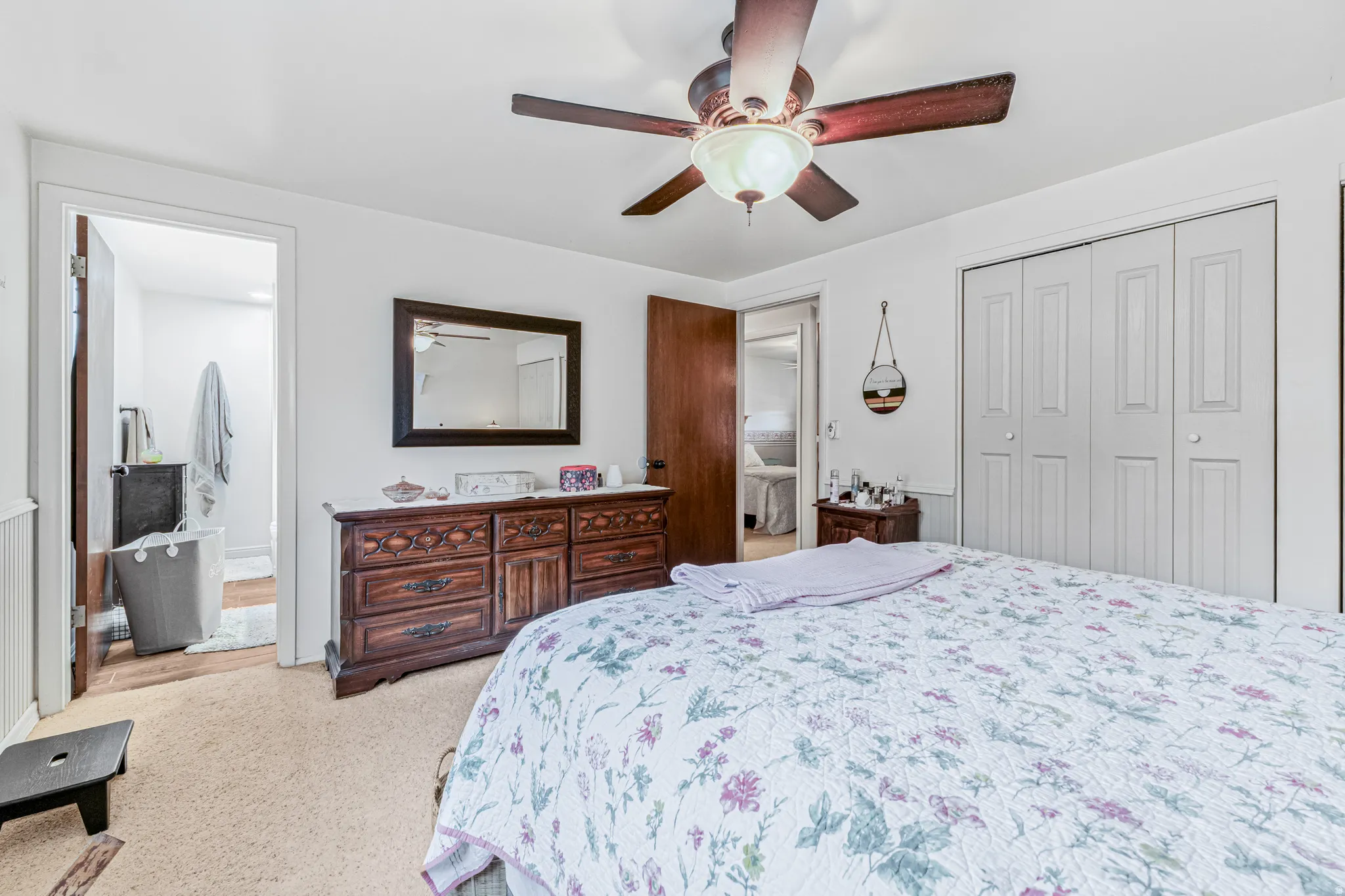Bedroom featuring ceiling fan, light colored carpet, a closet, and ensuite bath