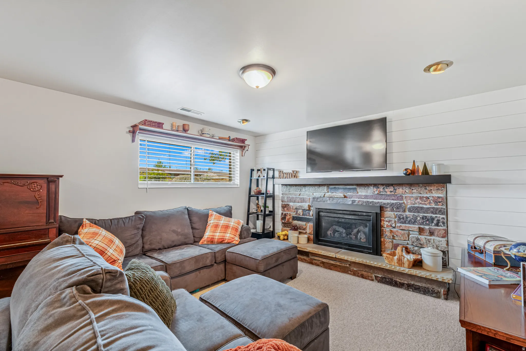 Family room featuring a stone fireplace, carpet floors, and wooden walls