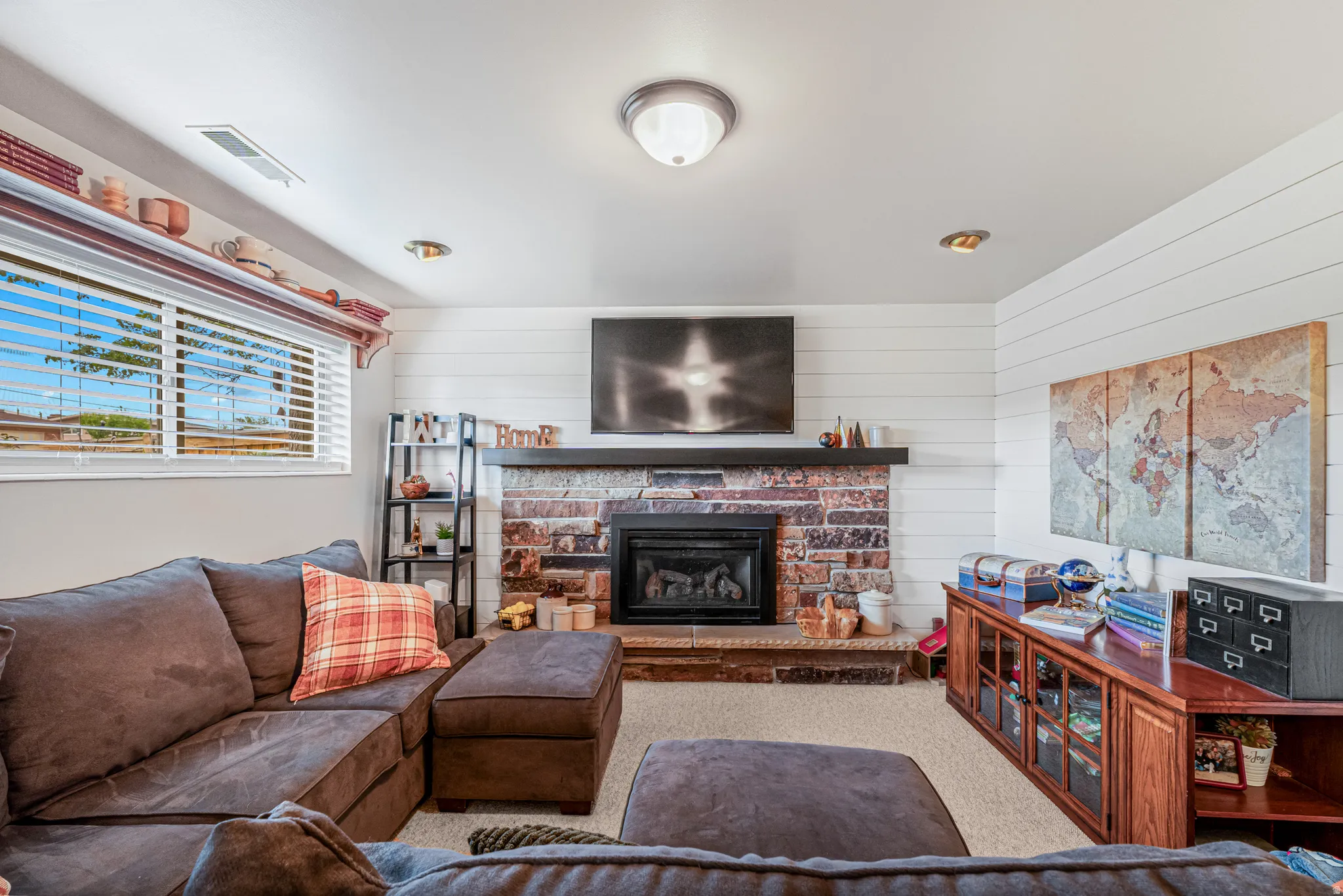 Carpeted living room with a fireplace and wooden walls