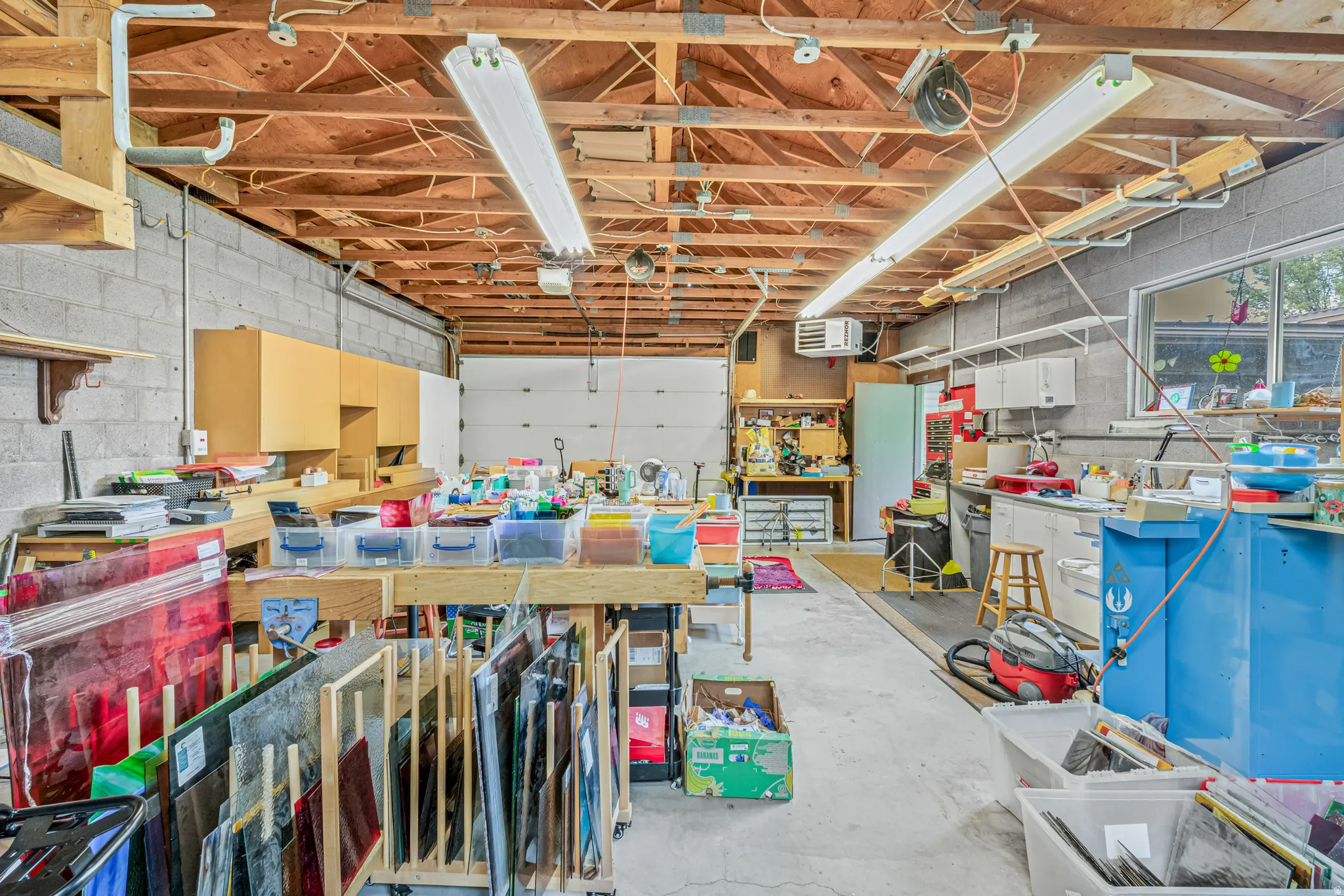 Garage featuring concrete block wall, a workshop area, and a heating unit