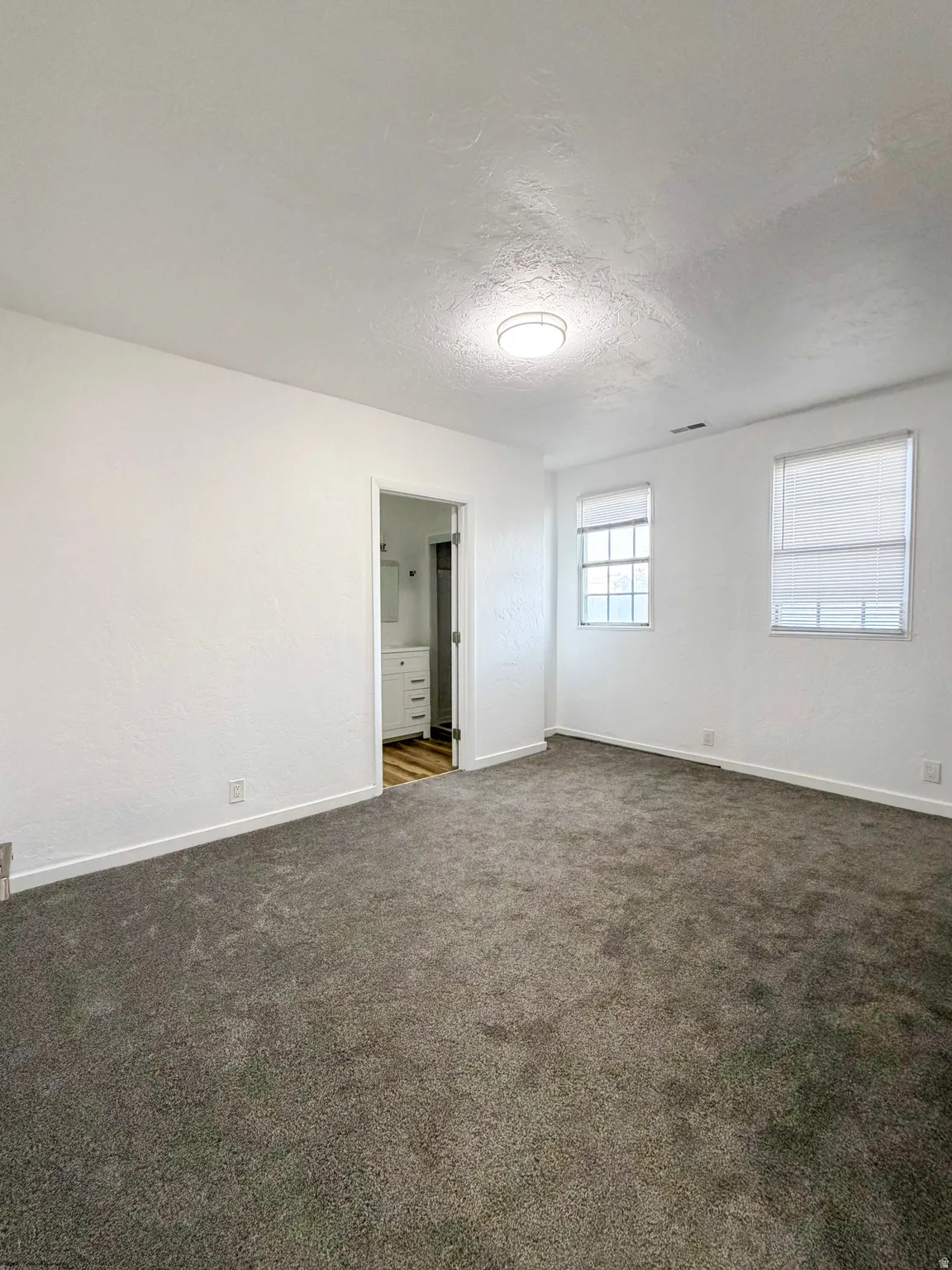Spare room with a textured ceiling and dark colored carpet