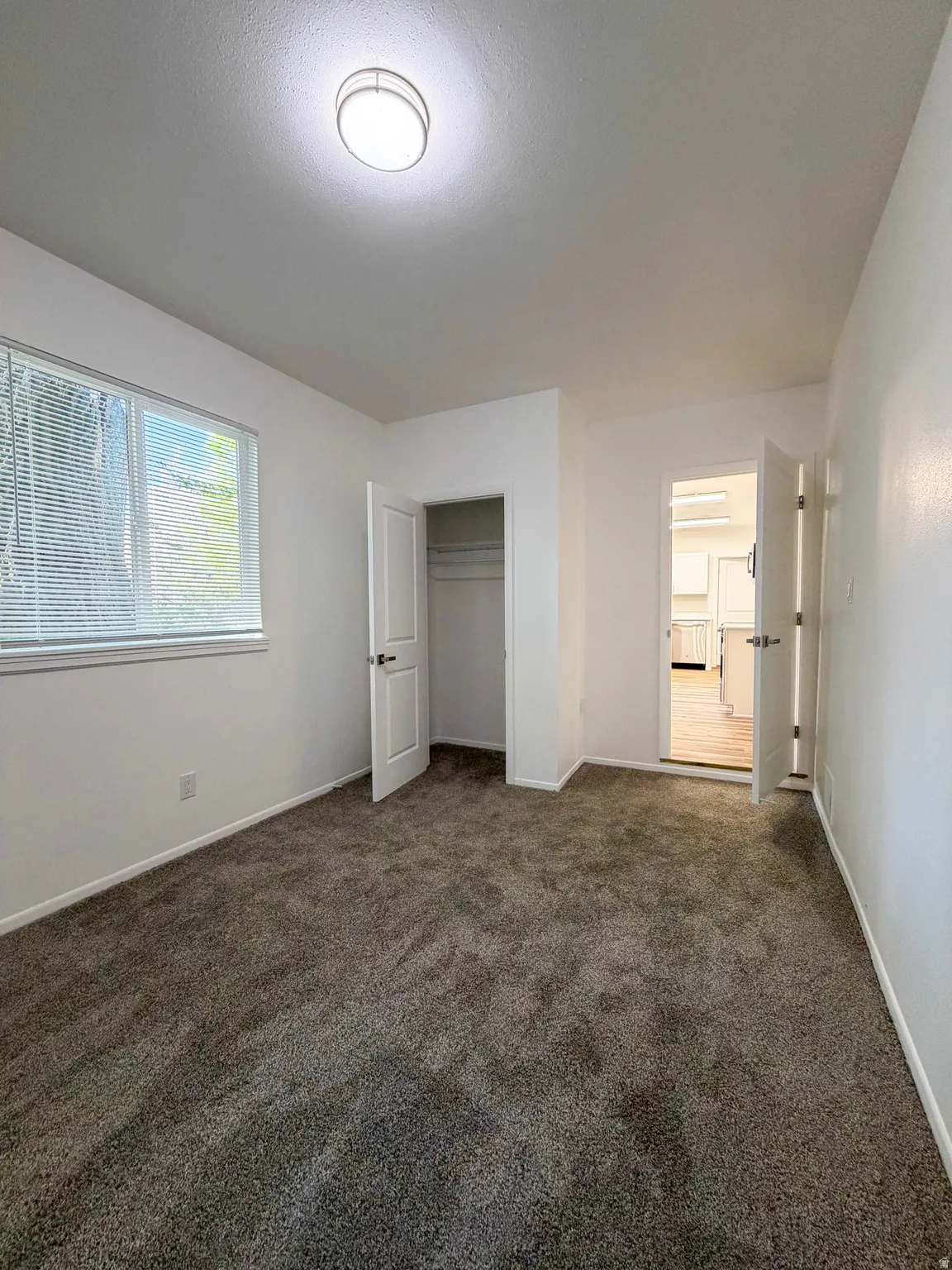 Unfurnished bedroom featuring dark carpet and a closet