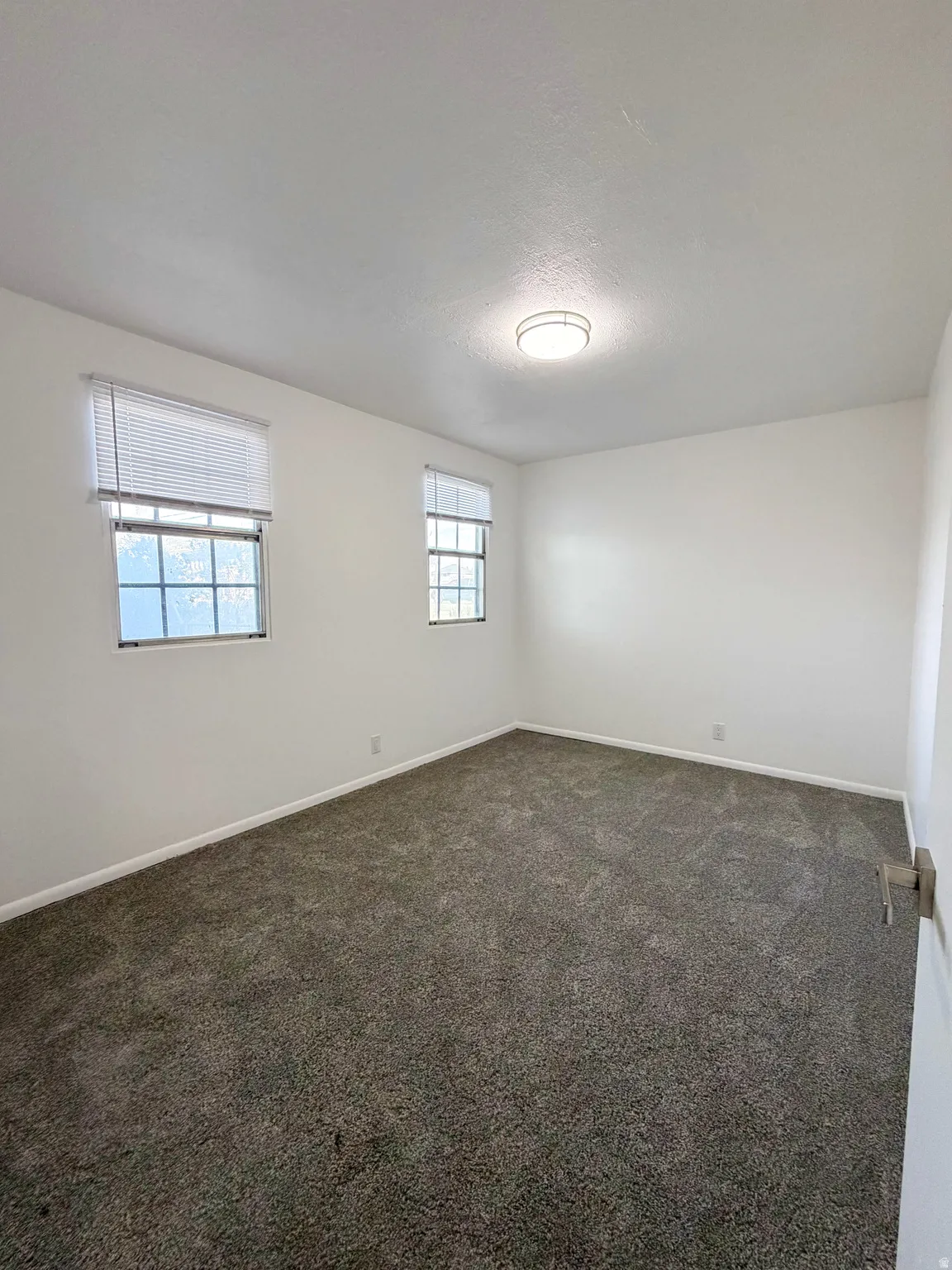 Empty room featuring dark colored carpet and a textured ceiling