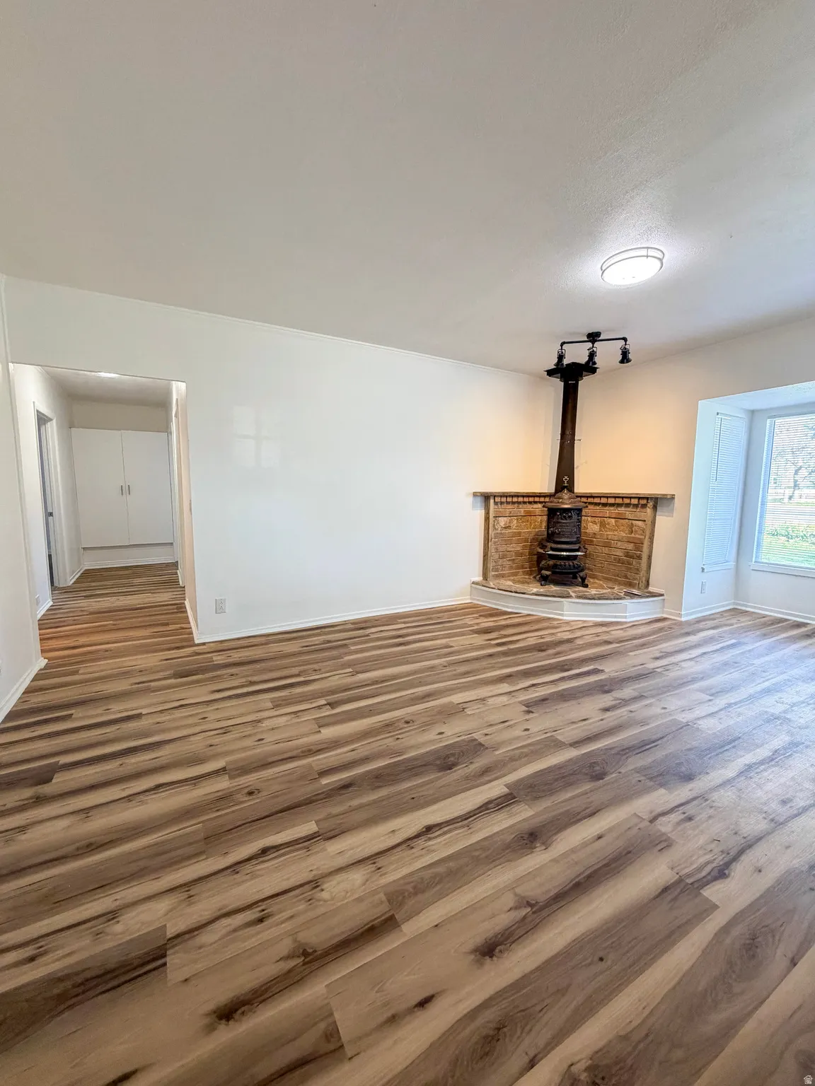 Unfurnished living room featuring wood finished floors and a wood stove