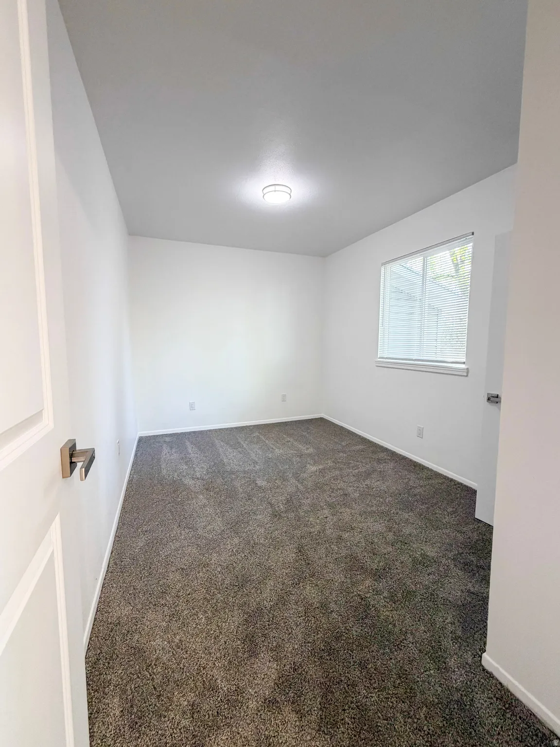Empty room featuring dark carpet and baseboards