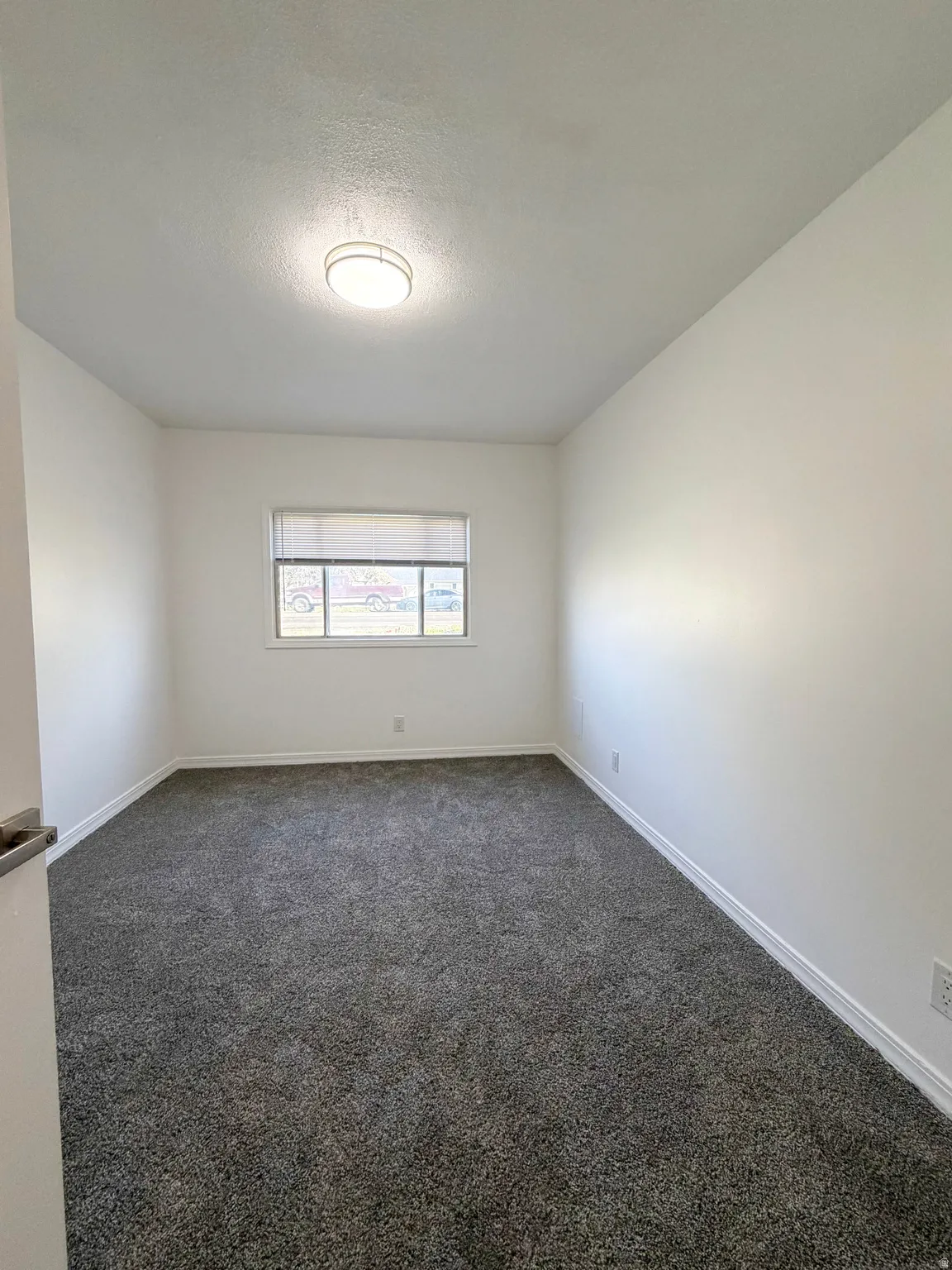 Unfurnished room with dark carpet and a textured ceiling