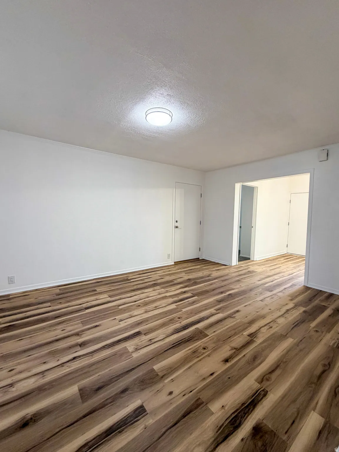 Empty room with a textured ceiling and wood finished floors