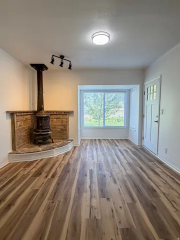 Unfurnished living room featuring dark wood finished floors, healthy amount of natural light, and a wood stove