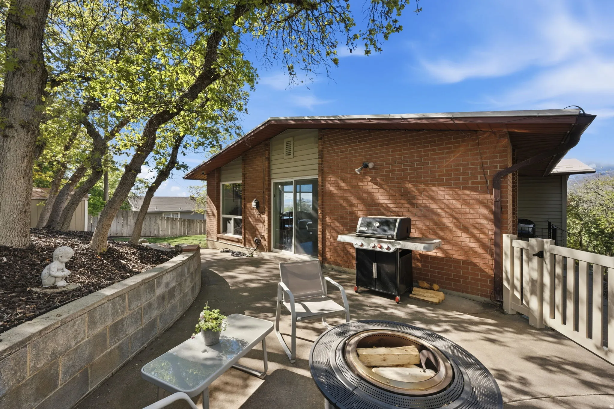 Fenced backyard with area for grilling, a patio, and an outdoor fire pit
