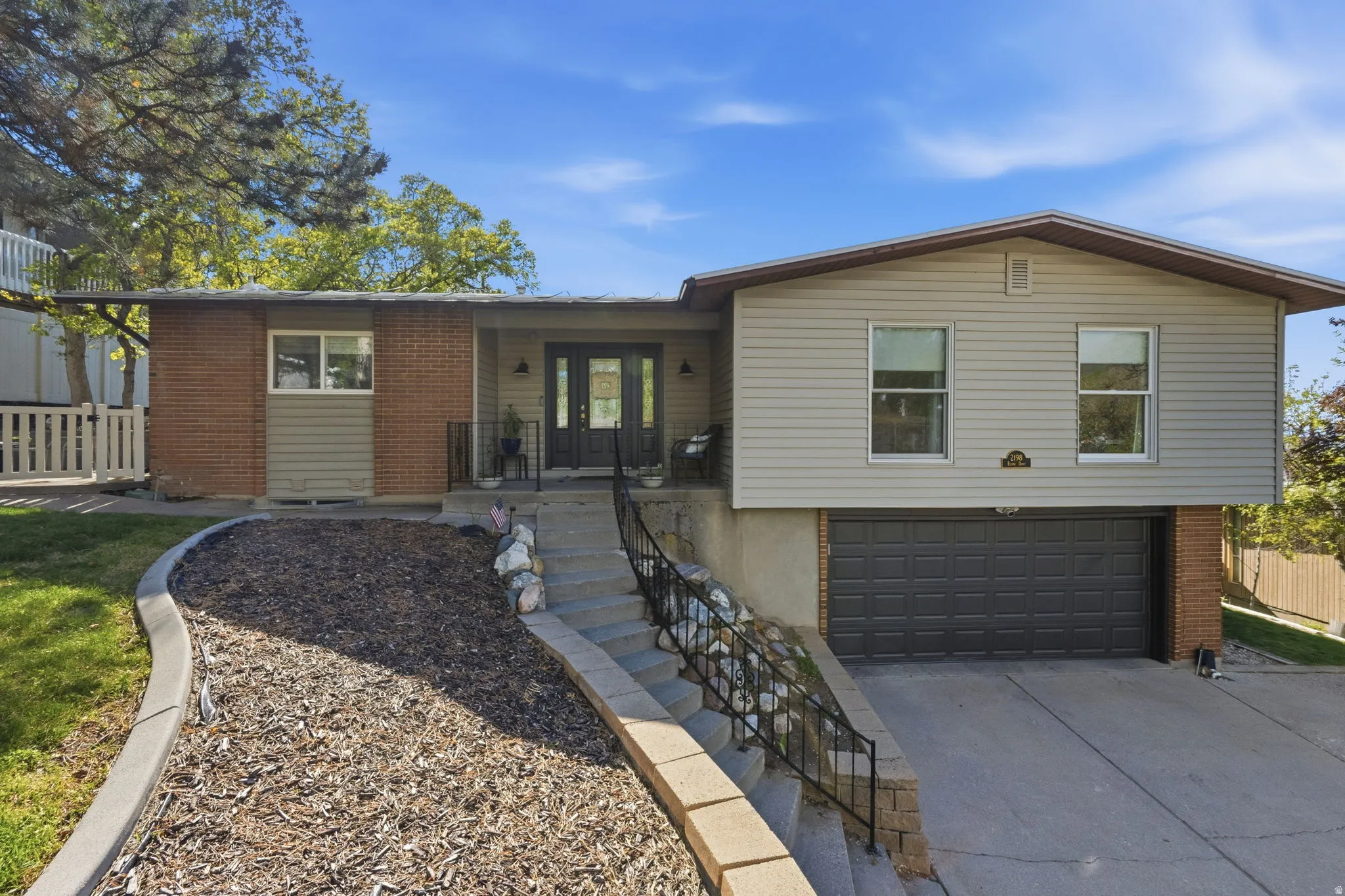 Ranch-style home featuring a garage, concrete driveway, brick siding, and french doors
