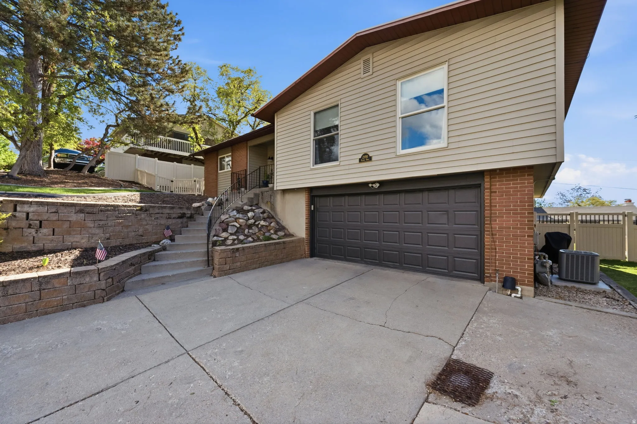 Rear view of house featuring a garage, driveway, and brick siding