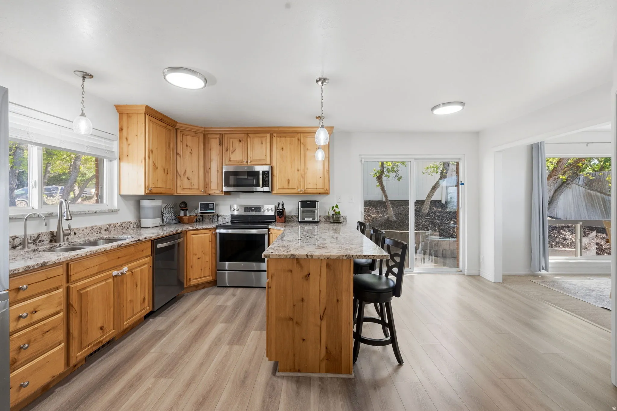 Kitchen with a peninsula, a kitchen bar, stainless steel appliances, and light wood-style flooring