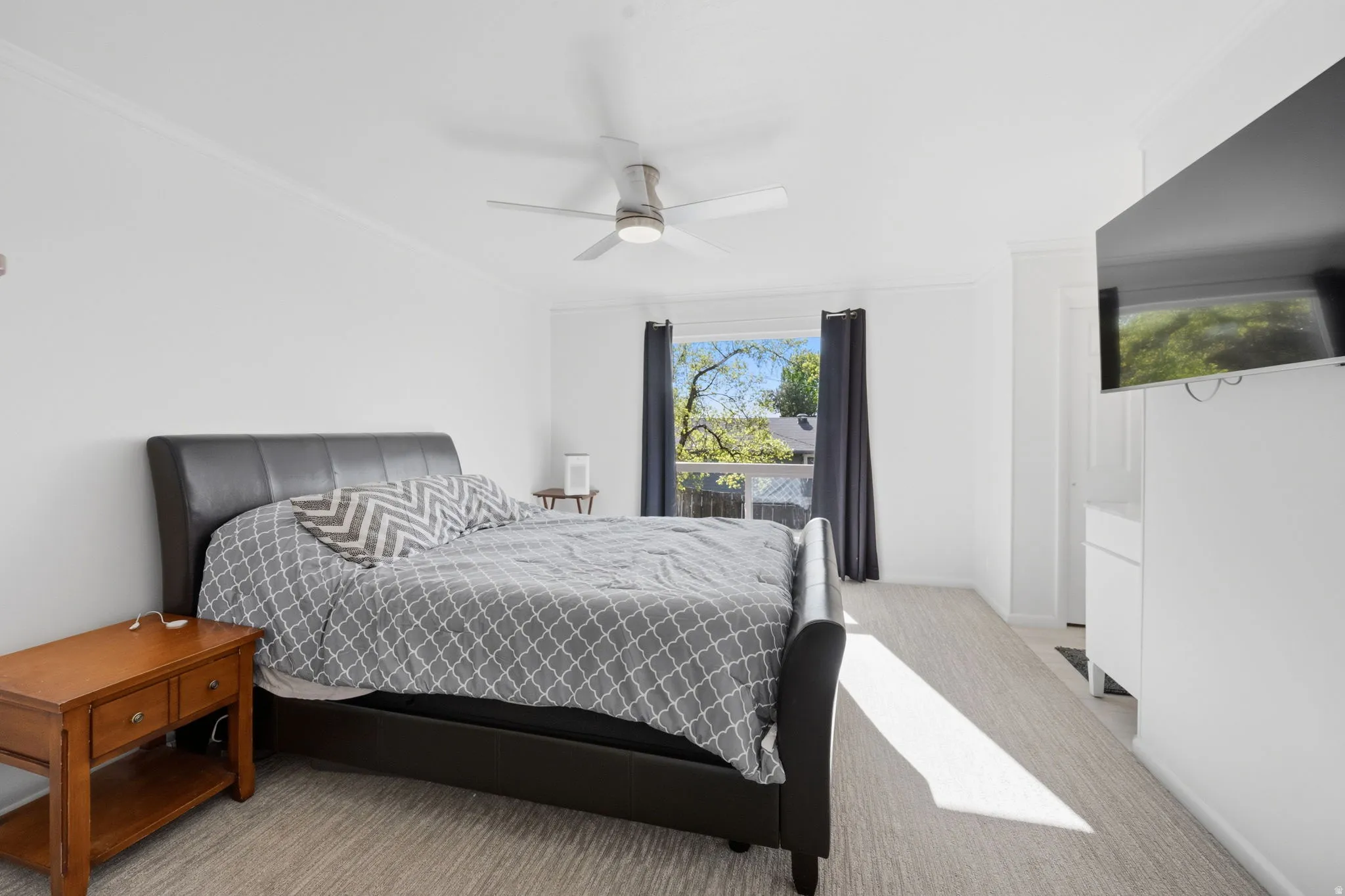 Bedroom with ornamental molding, a ceiling fan, and light colored carpet