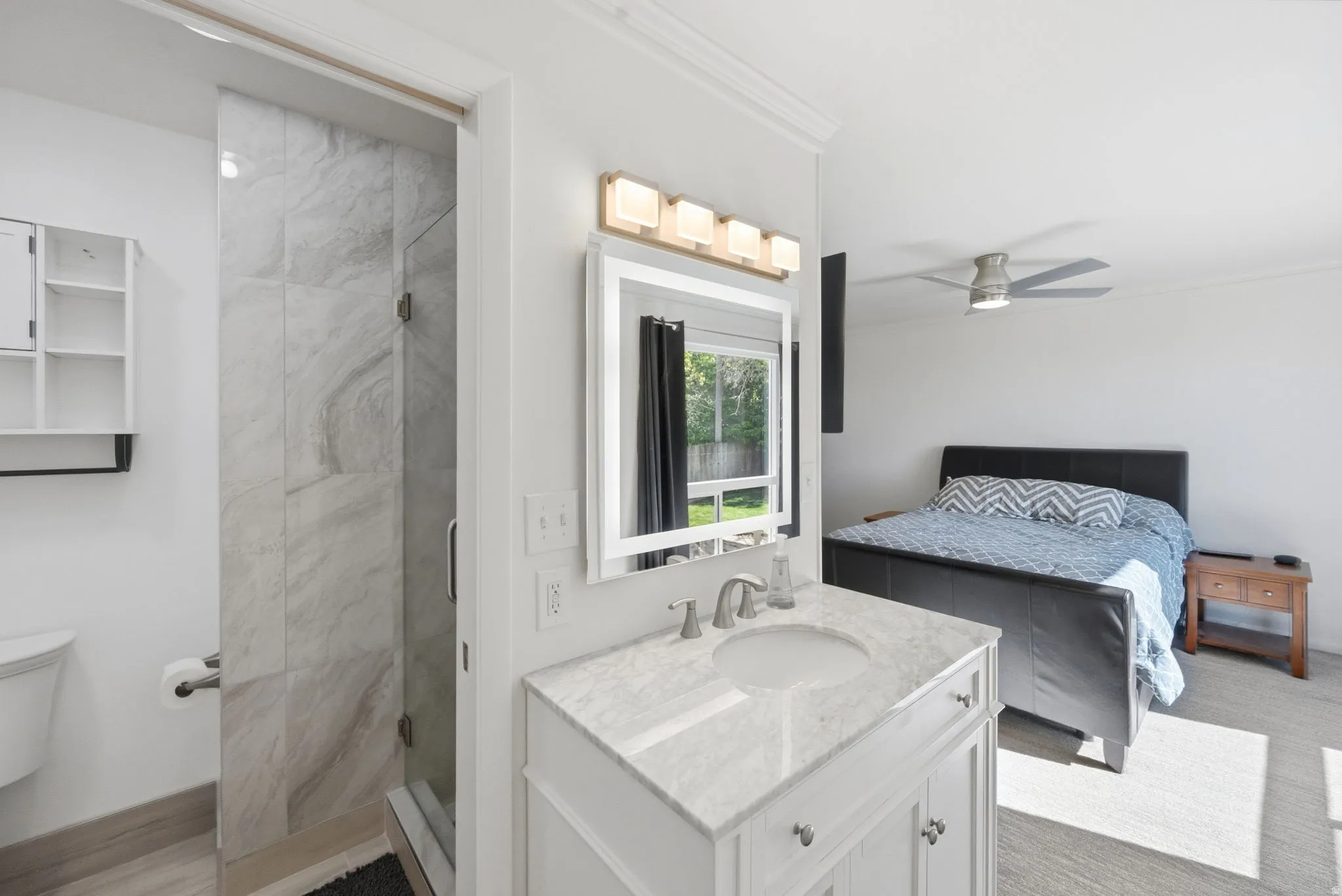 Ensuite bathroom featuring vanity, a stall shower, ornamental molding, and a ceiling fan