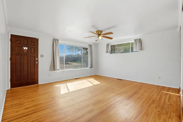 Entrance foyer featuring light wood finished floors, a ceiling fan, plenty of natural light, and crown molding