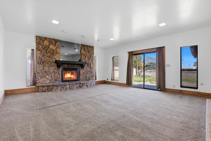 Unfurnished living room featuring carpet and a stone fireplace