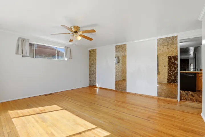 Empty room with light wood-type flooring, ornamental molding, and a ceiling fan
