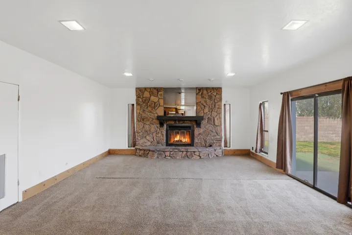 Unfurnished living room with light carpet and a stone fireplace