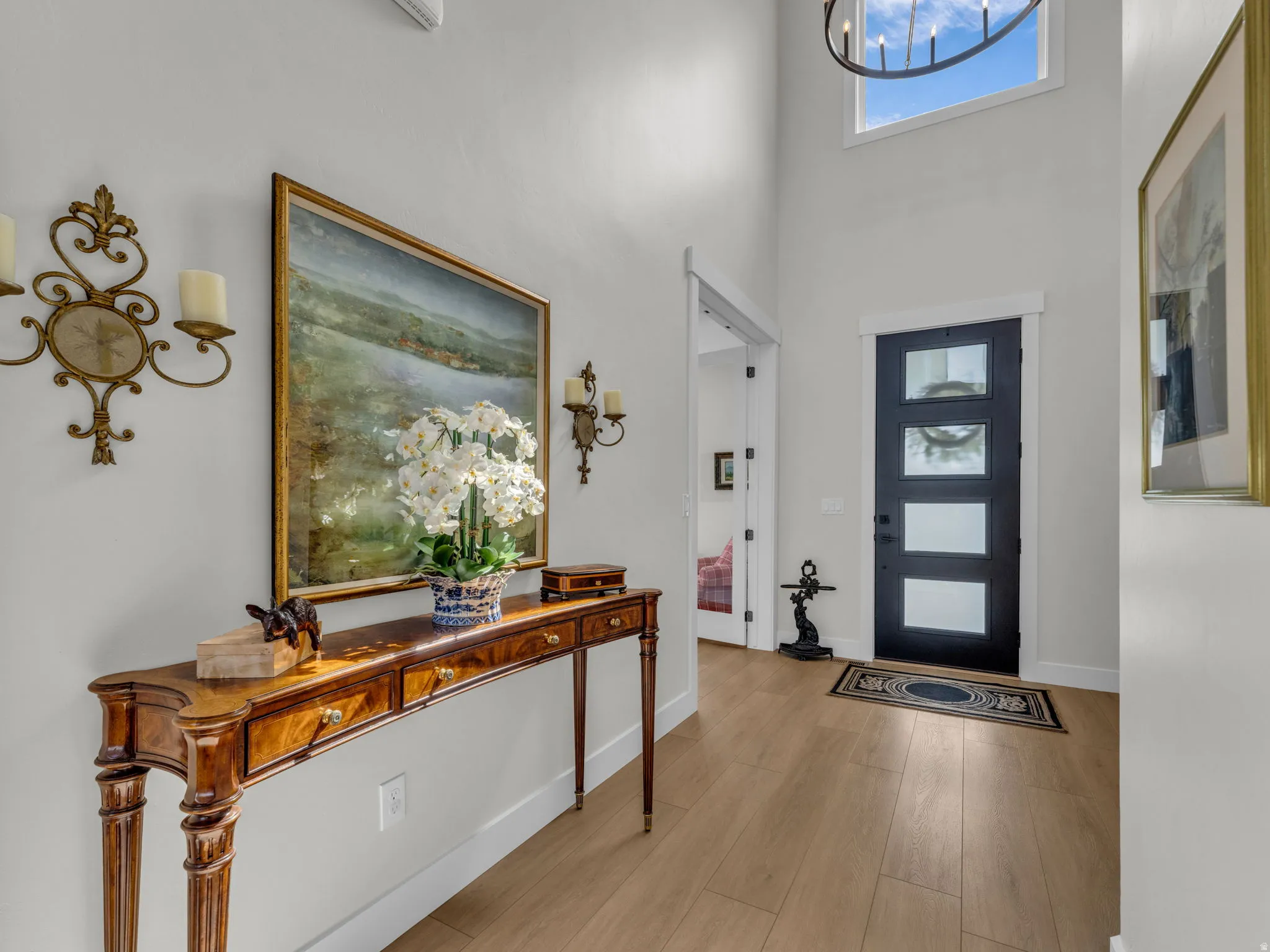 Entryway featuring light wood finished floors, healthy amount of natural light, and a high ceiling