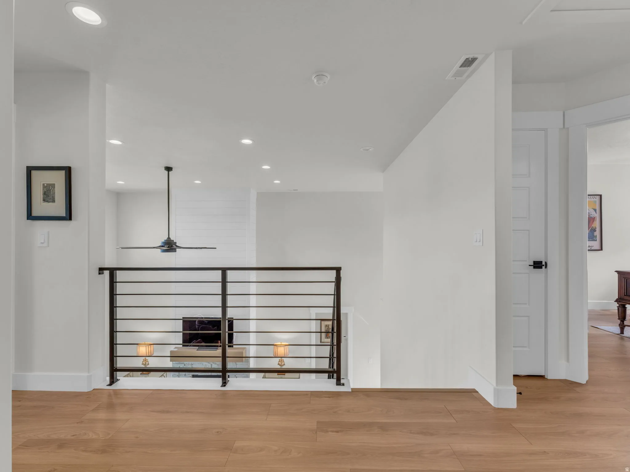 Hallway featuring light wood-style flooring, recessed lighting, and an upstairs landing