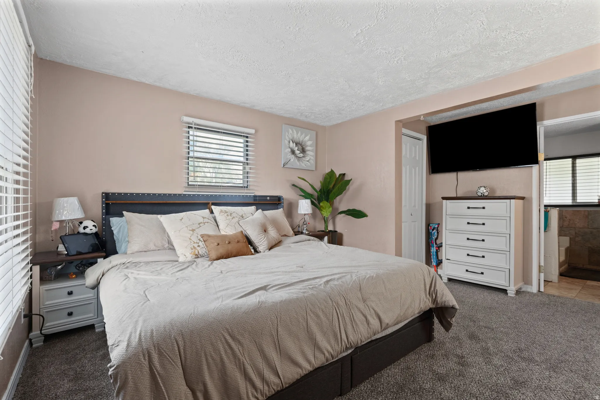 Bedroom with carpet flooring, a textured ceiling, ensuite bathroom, and a closet