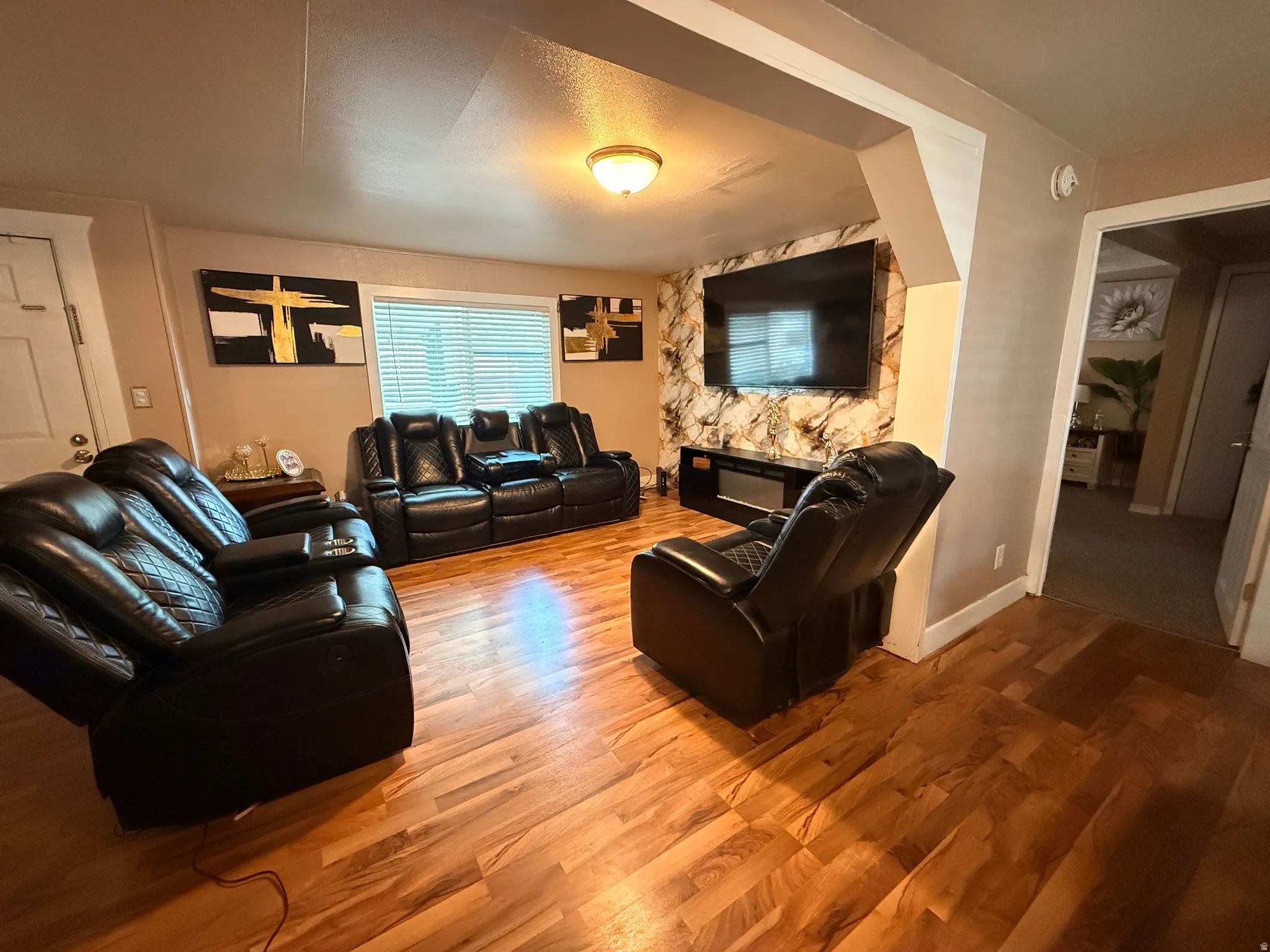 Wood-finish flooring throughout, with neutral wall paint and a window featuring horizontal blinds