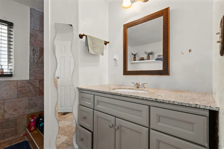 Full bathroom featuring vanity, a textured wall, and stone tile floors