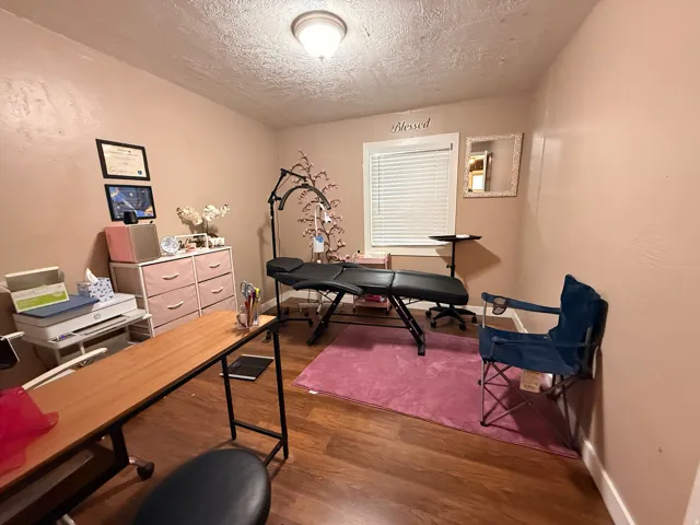 Wood-finish flooring with painted walls, ceiling light fixture, and a window with blinds